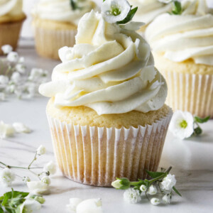 A white chocolate cupcake next to small white flowers