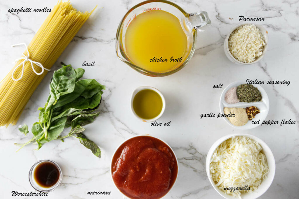 Ingredients for baked spaghetti: chicken broth, spaghetti noodles, parmesan, garlic powder, salt, Italian seasoning, red pepper flakes, mozzarella, marinara, Worcestershire, and basil.