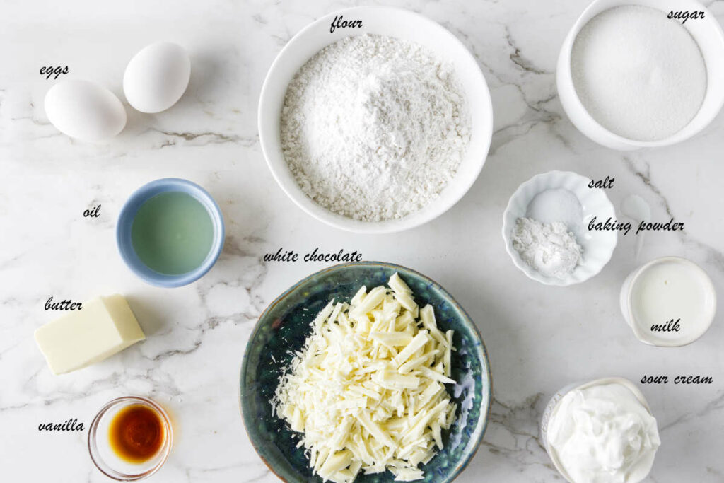 Ingredients for cupcakes: eggs, flour, sugar, salt, baking powder, milk, sour cream, vanilla, butter, oil, and white chocolate.