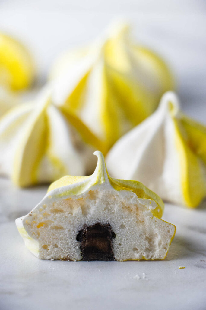 A lemon meringue cut in half and showing a chocolate truffle in the center.