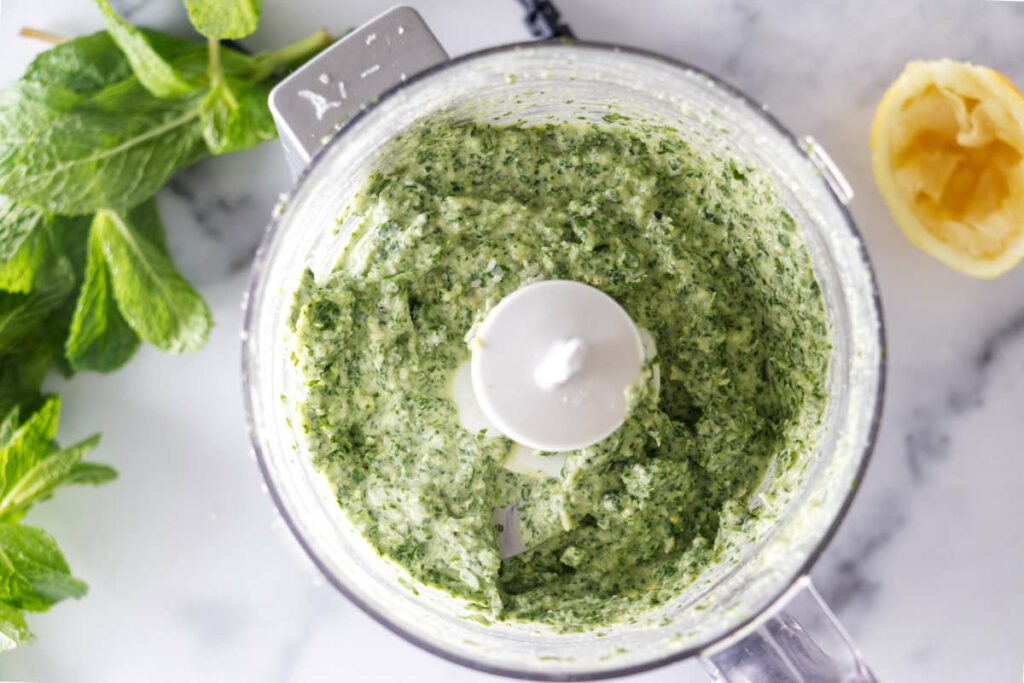 A food processor with freshly blended mint and Parmesan sauce.