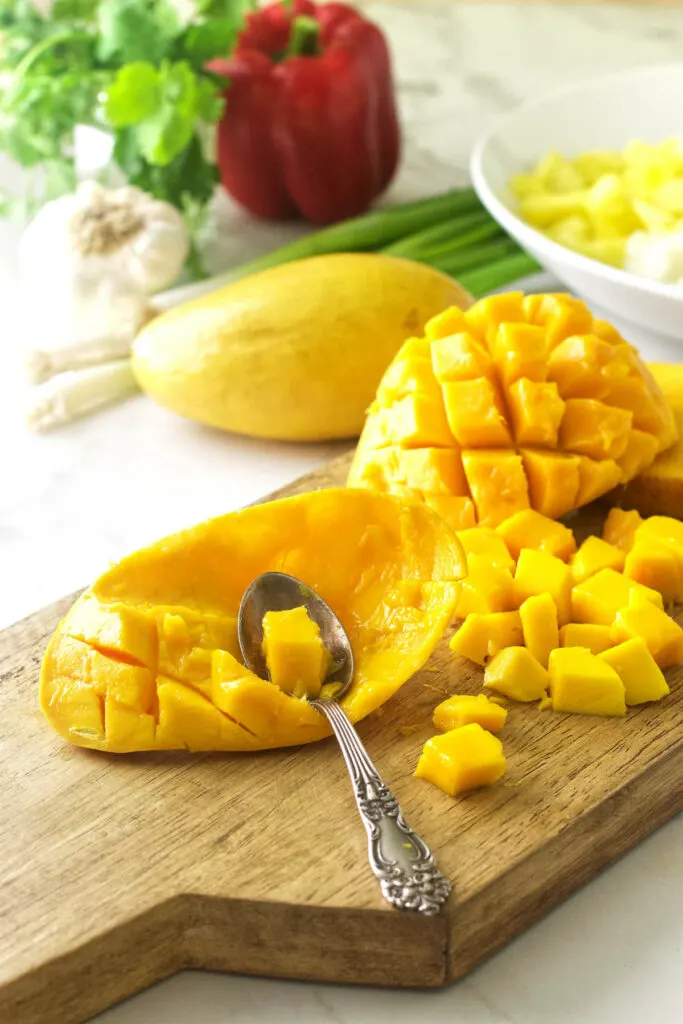 Scooping chunks of fruit out of a mango.