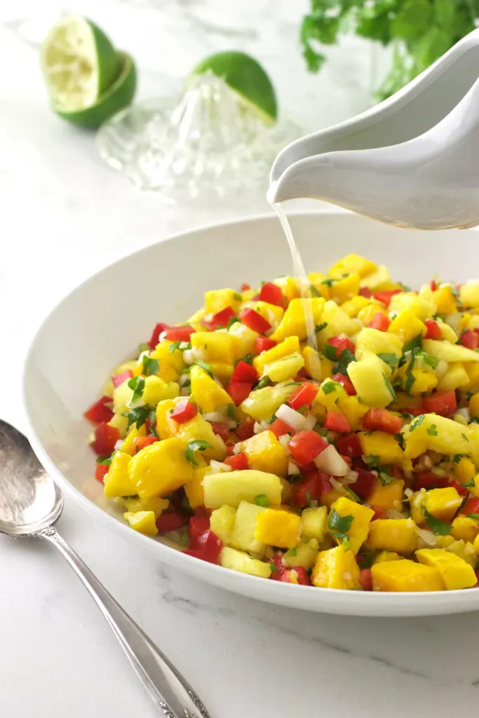Combining the ingredients for mango pineapple salsa in a mixing bowl.