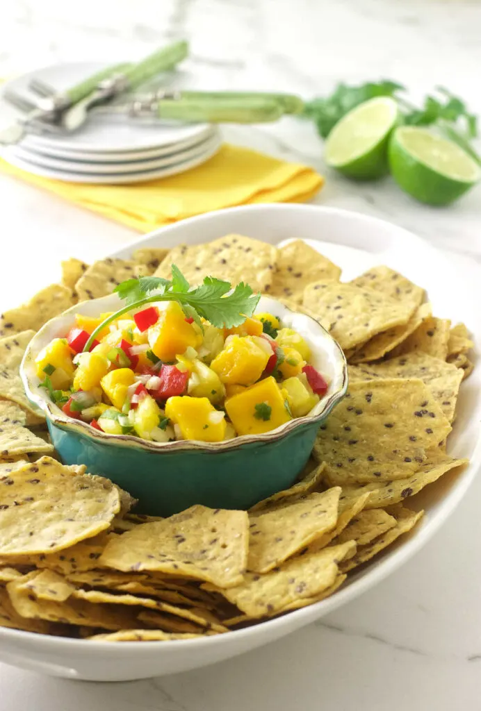 A dish of mango pineapple salsa surrounded by chips.