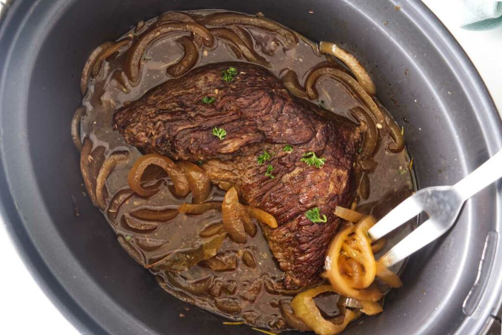 A tri tip in a slow cooker with onions.
