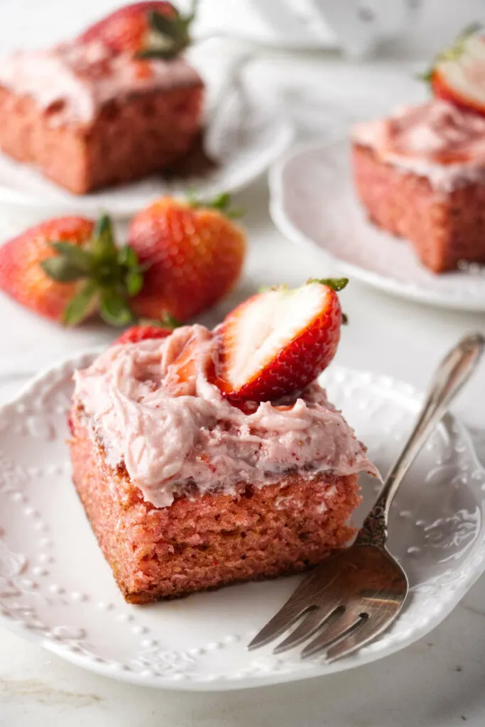 Three slices of strawberry cake on serving plates.