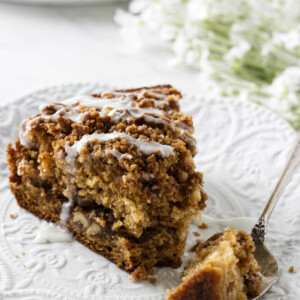 A slice of applesauce cake on a white plate with a fork.