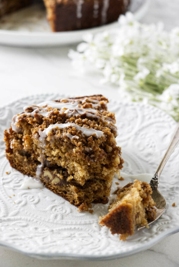 A slice of applesauce cake on a white plate with a fork.