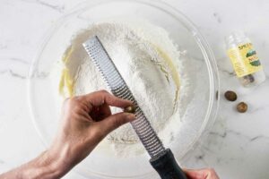 Grating fresh nutmeg into donut batter.