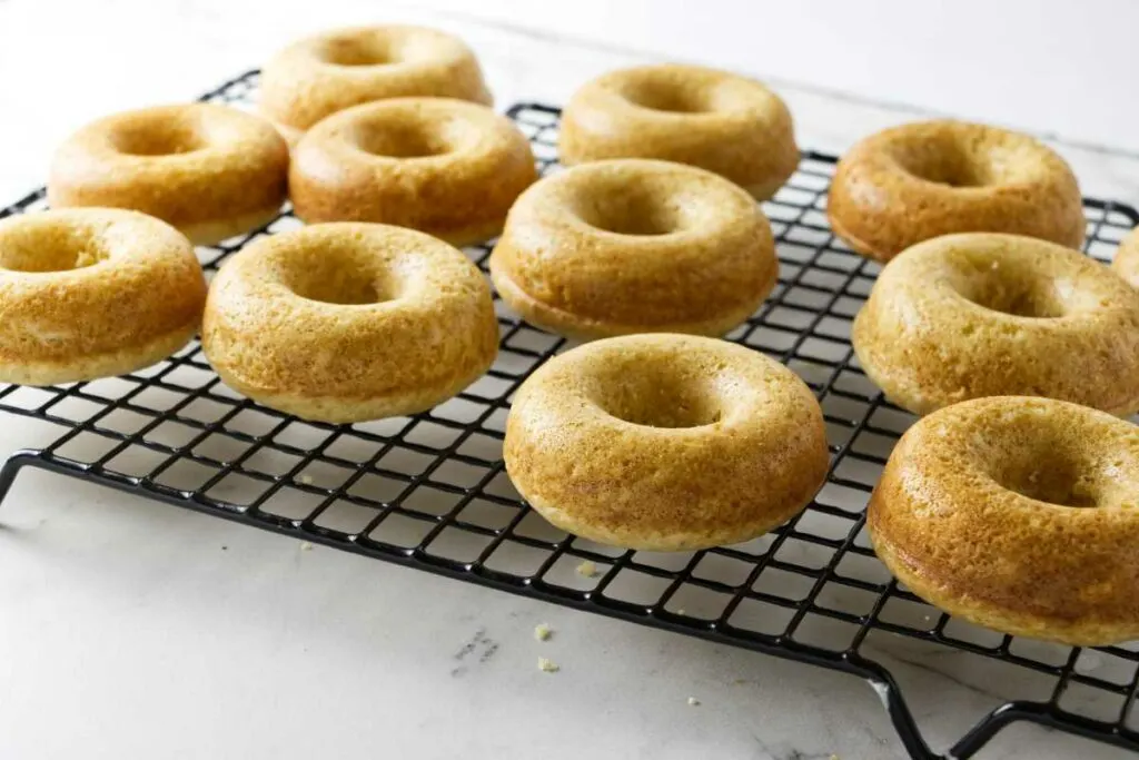 Cooling sourdough cake donuts on a wire rack.