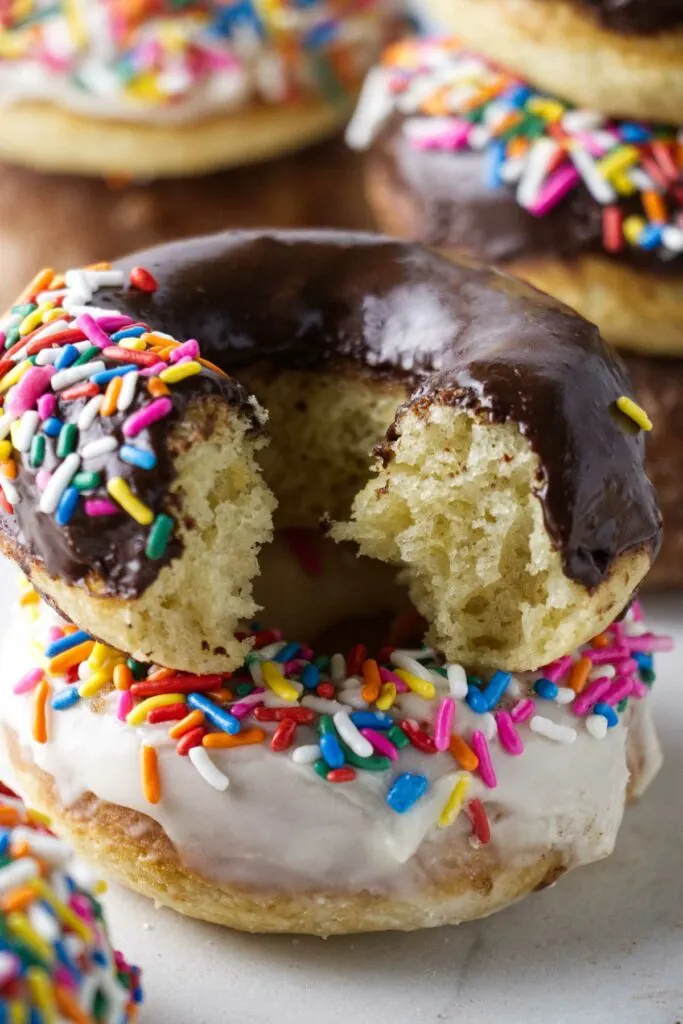 A chocolate glazed sourdough cake donut on top of a vanilla glazed donut.