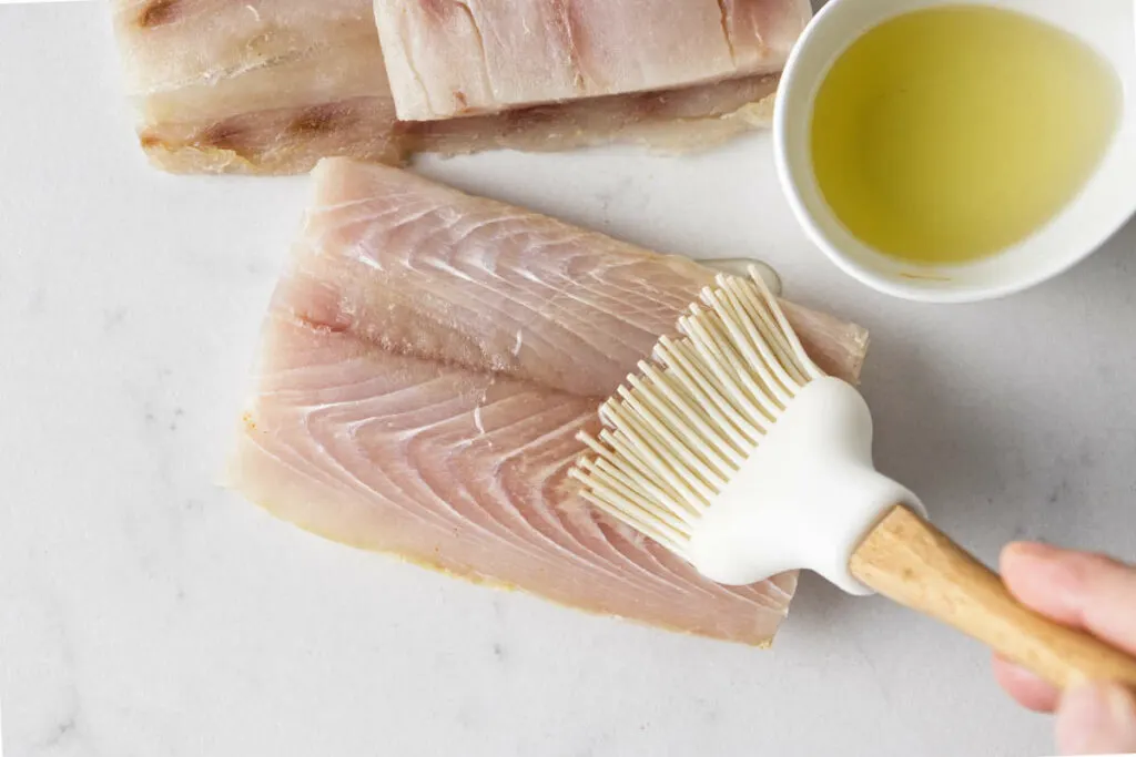 Brushing oil on a filet of fish.