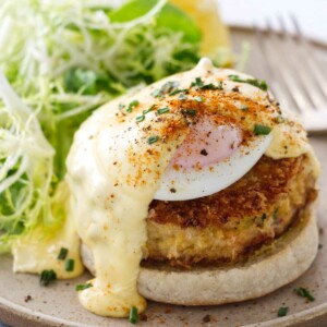 A serving of crab benedict on a plate with salad and a fork.