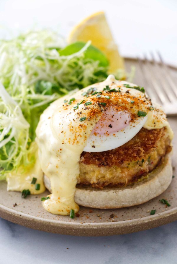 A serving of crab benedict on a plate with salad and a fork.