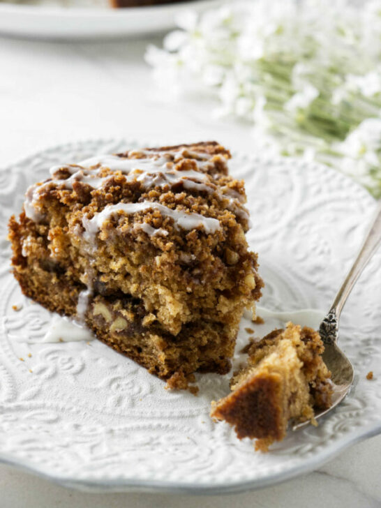 A slice of applesauce cake on a white plate with a fork.