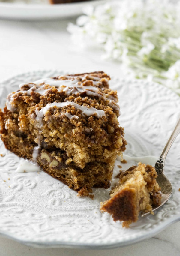 A slice of applesauce cake on a white plate with a fork.