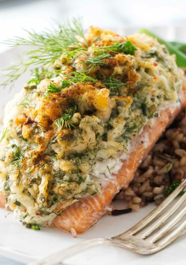 A serving of crab and shrimp stuffed salmon on a bed of wild rice blend. A fork on the plate in the foreground.