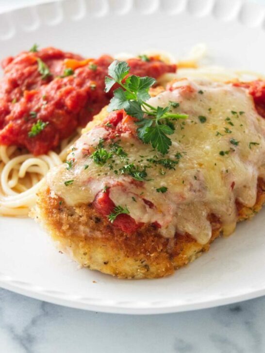 Olive Garden Chicken Parmesan on a plate with spaghetti and marinara sauce.