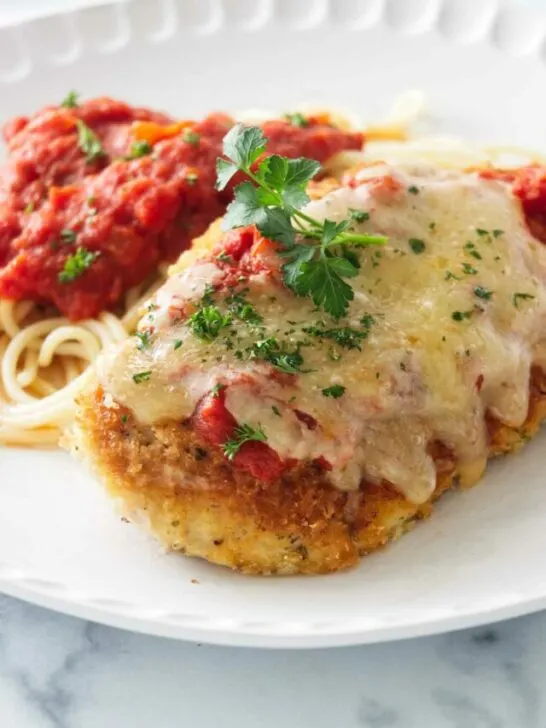 Olive Garden Chicken Parmesan on a plate with spaghetti and marinara sauce.