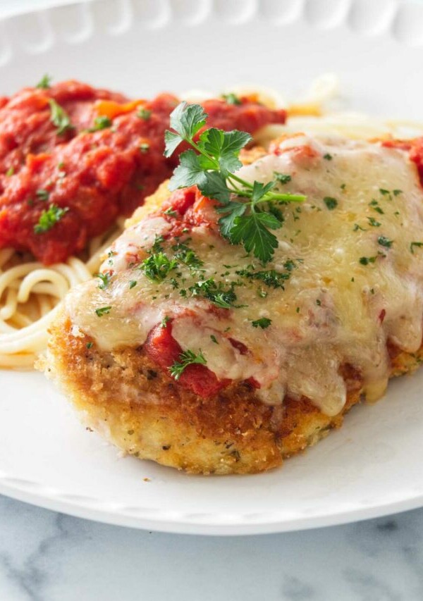 Olive Garden Chicken Parmesan on a plate with spaghetti and marinara sauce.