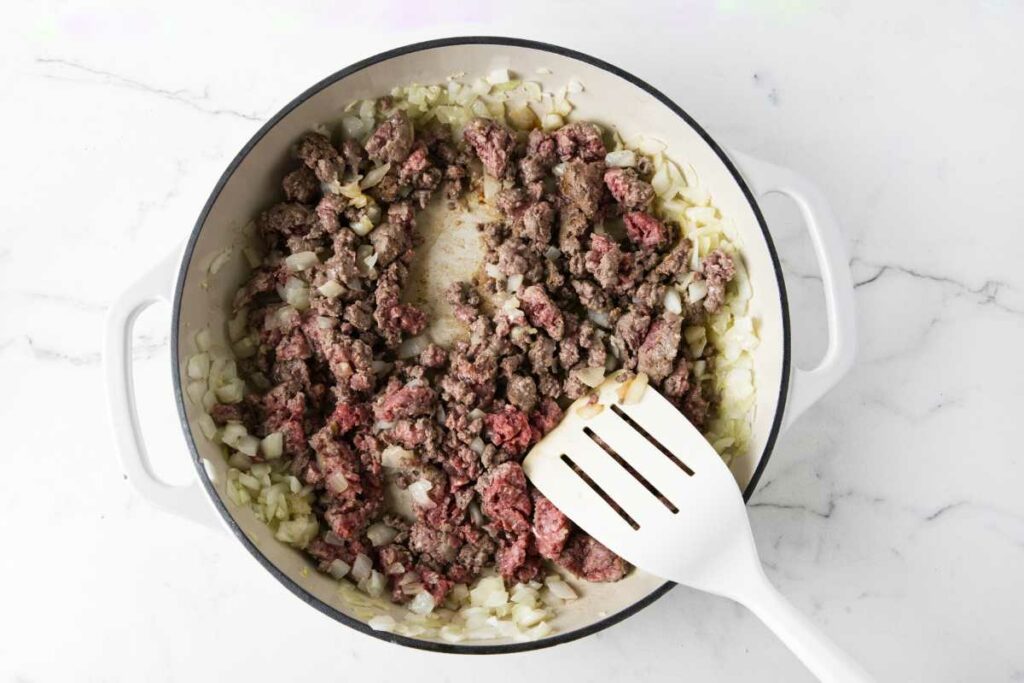 Browning ground beef in a skillet with onions and garlic.