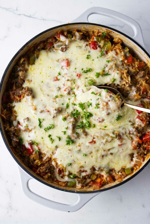 A spoon scooping out a serving of ground beef and rice casserole.