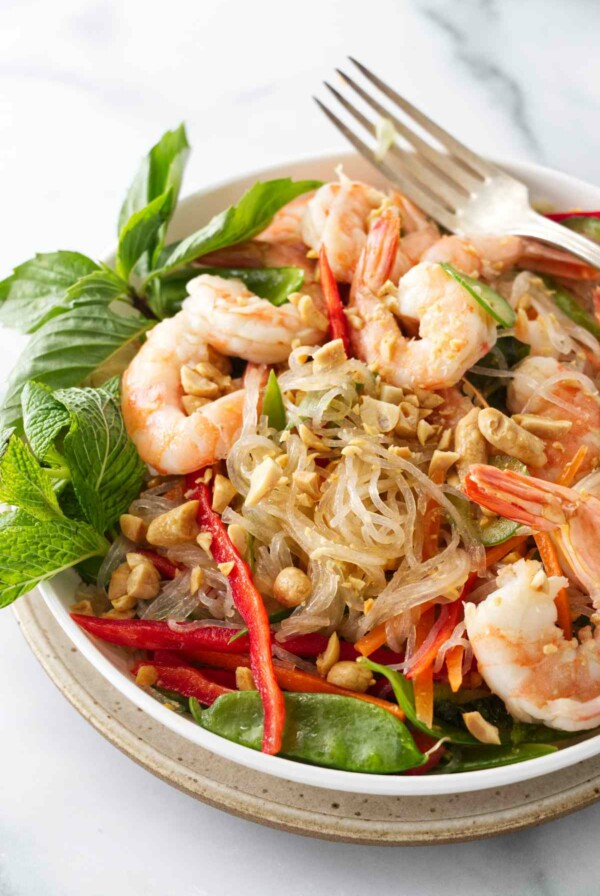 A serving of Thai glass noodle salad with shrimp and garnished with mint, Thai basil and chopped peanuts.