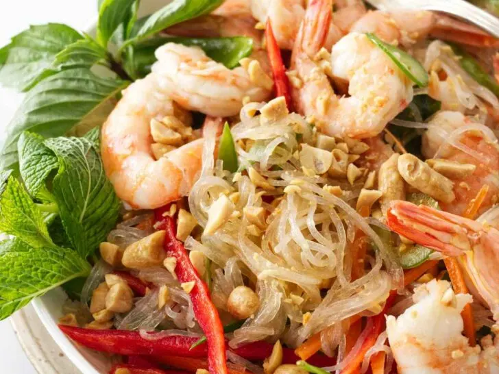 A serving of Thai glass noodle salad with shrimp and garnished with mint, Thai basil and chopped peanuts.