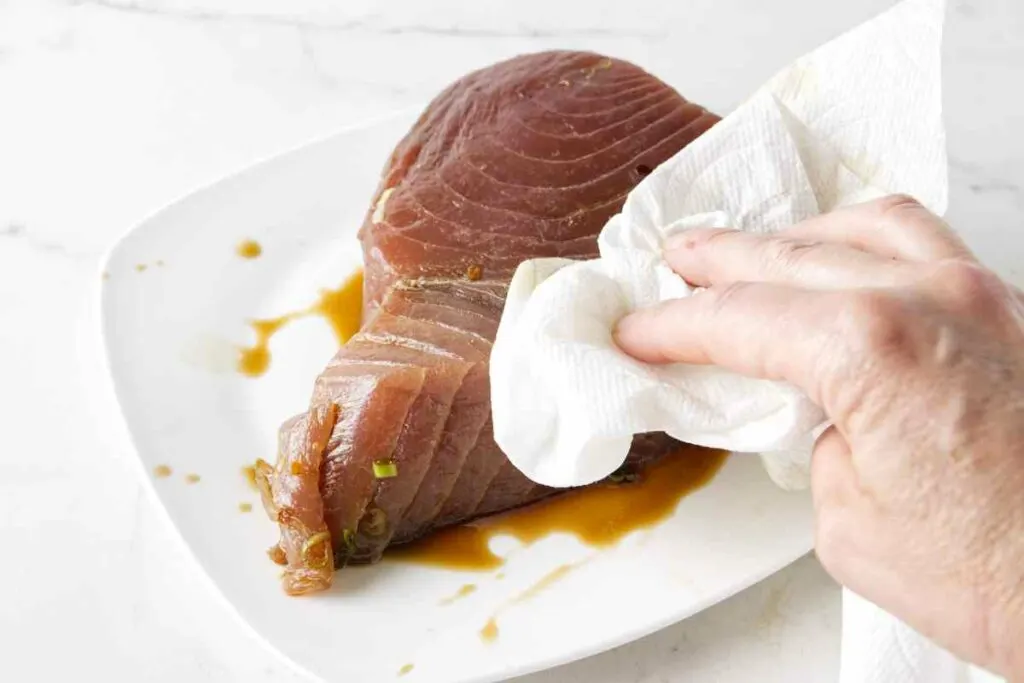 Drying marinade off the surface of a tuna steak.