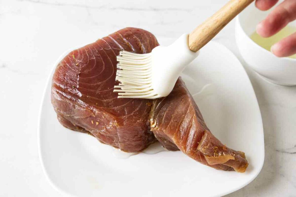 Brushing oil on a tuna steak.