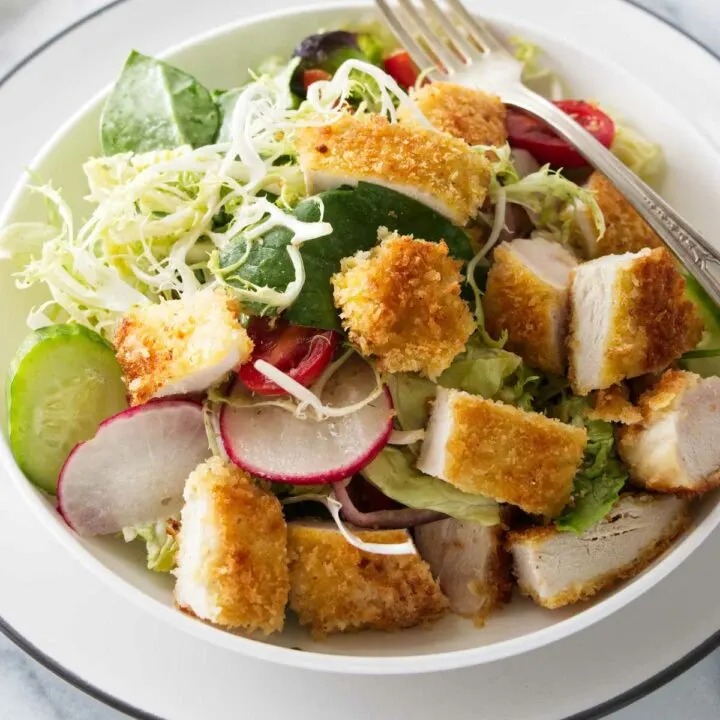 A serving of crispy chicken salad in a dish with a fork.