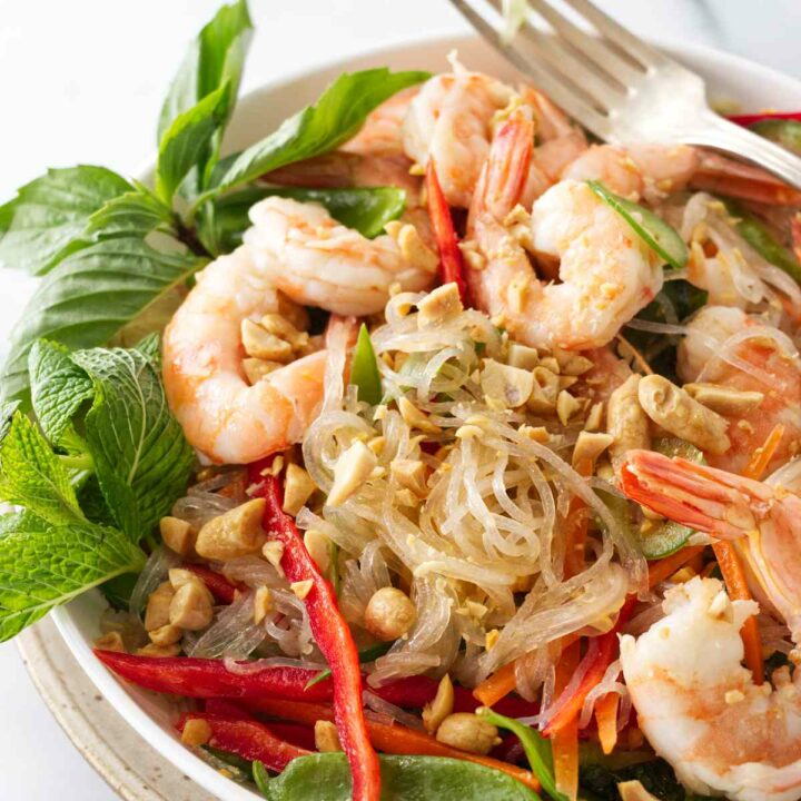 Close up photo of a serving dish and fork andThai glass noodle salad with shrimp.