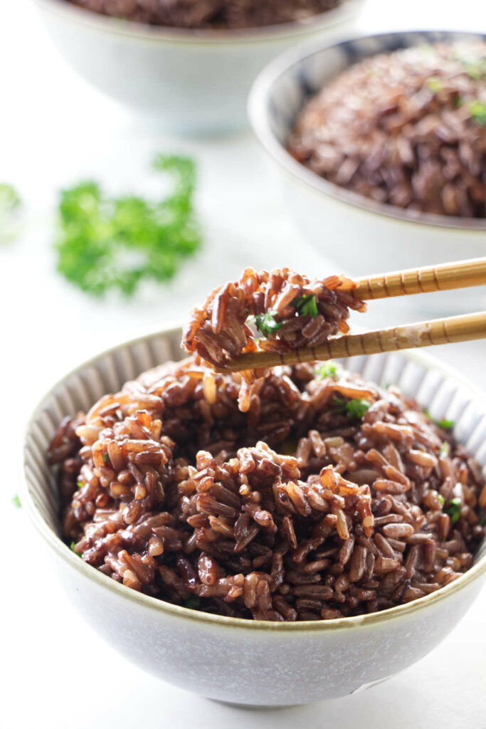 Chopsticks with a bite of Instant Pot Whole Grain Red rice.