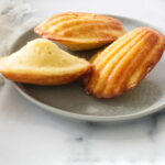 Three lemon madeleine cookies on a plate.