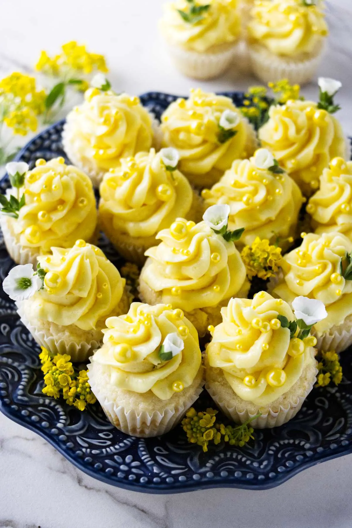 Several miniature lemon cupcakes on a blue plate.
