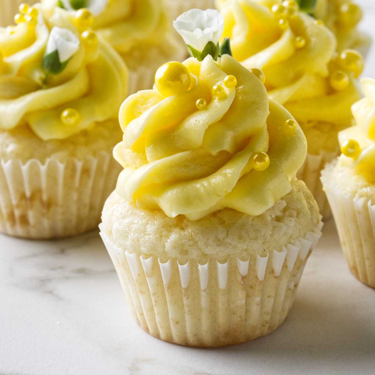 Several min lemon cupcakes topped with a swirl of lemon condensed milk buttercream.