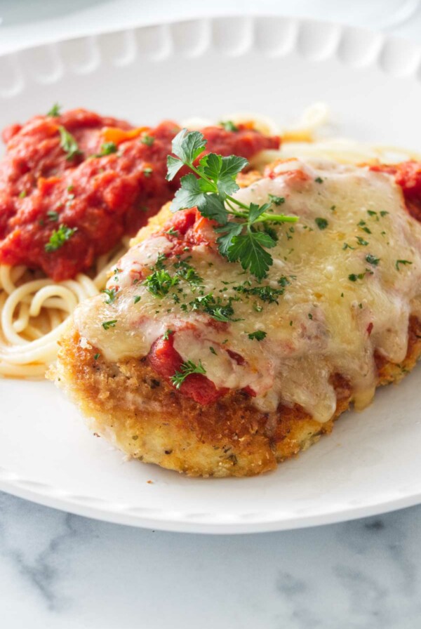 Olive Garden Chicken Parmesan on a plate with spaghetti and marinara sauce.