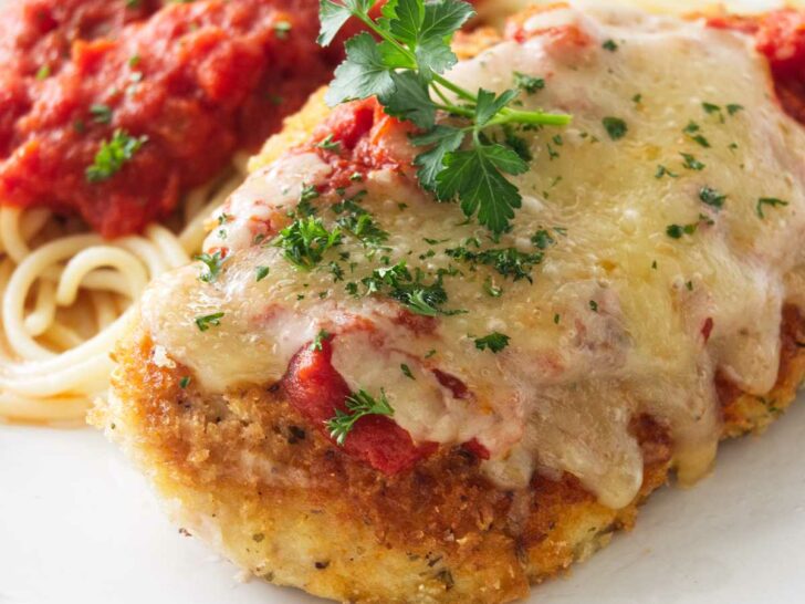 Olive Garden Chicken Parmesan on a plate with spaghetti and marinara sauce.