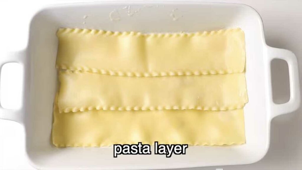Adding a layer of lasagna noodles in a dish.