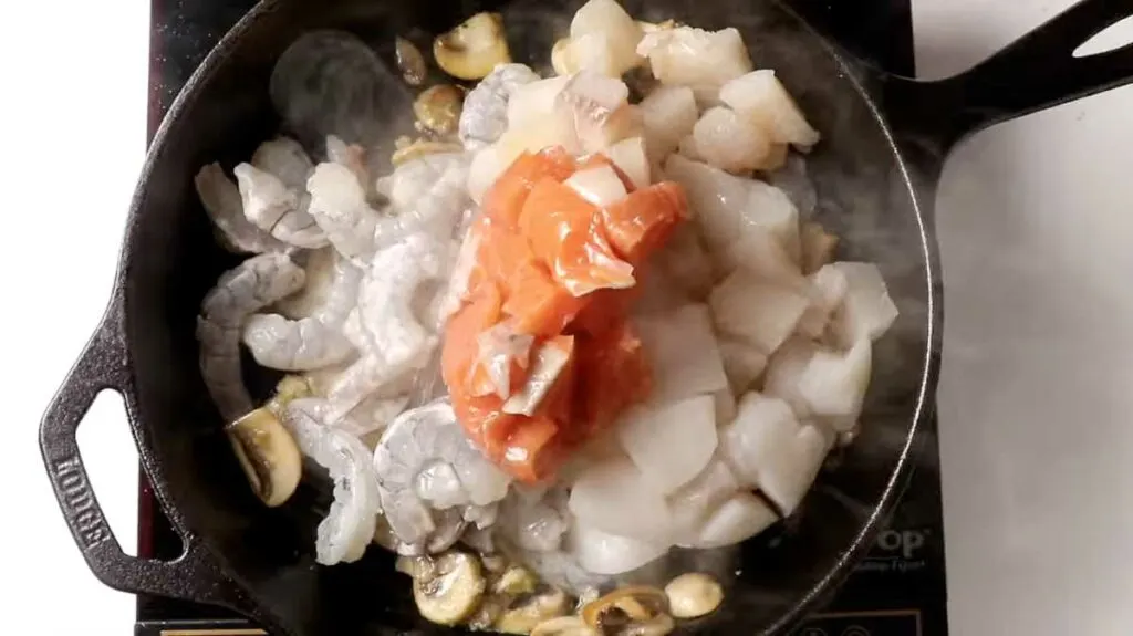 Adding the seafood to a hot saucepan.