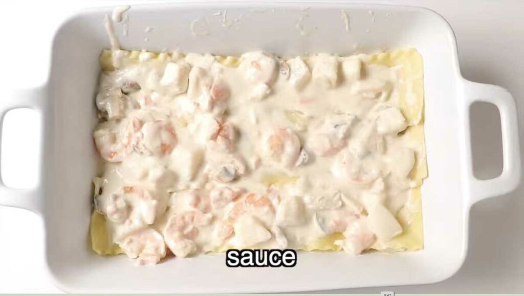 Layering the seafood and sauce mixture in the lasagna.