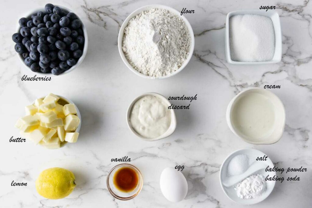 Scone ingredients: blueberries, flour, sugar, sourdough discard, cream, baking powder, salt, egg, vanilla, lemon, and butter.