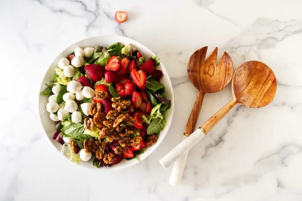 Over head view of the strawberry walnut salad and a salad fork and spoon.