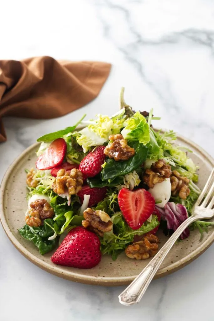 strawberry walnut salad on a serving plate with a fork.