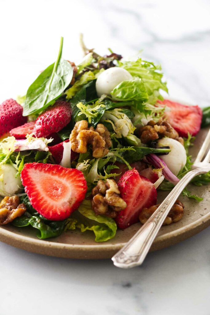 Close view of a serving of strawberry walnut salad.