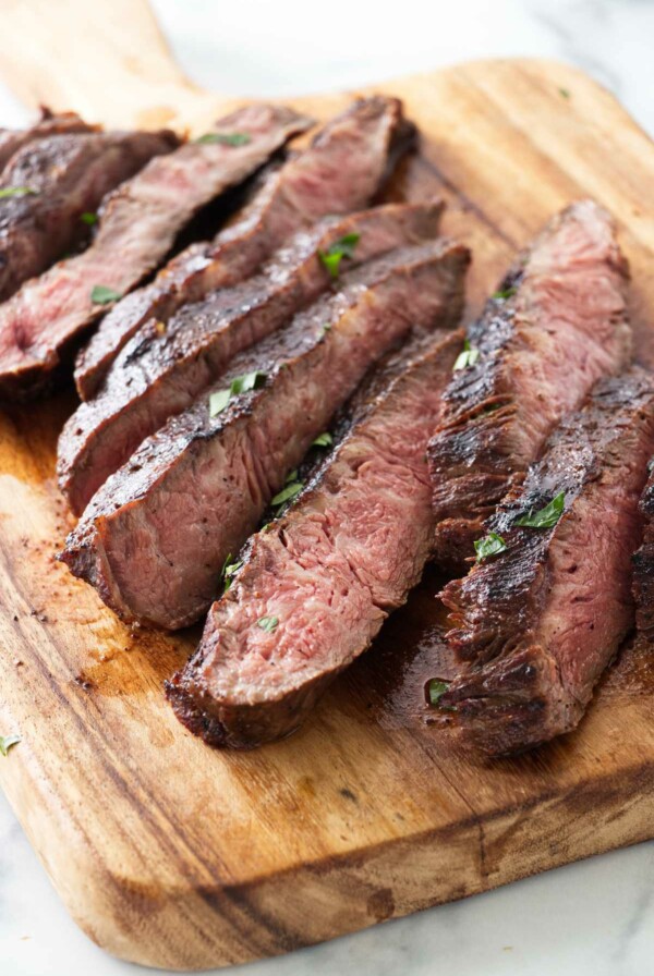 Sliced sous vide flat iron steak on a cutting board.