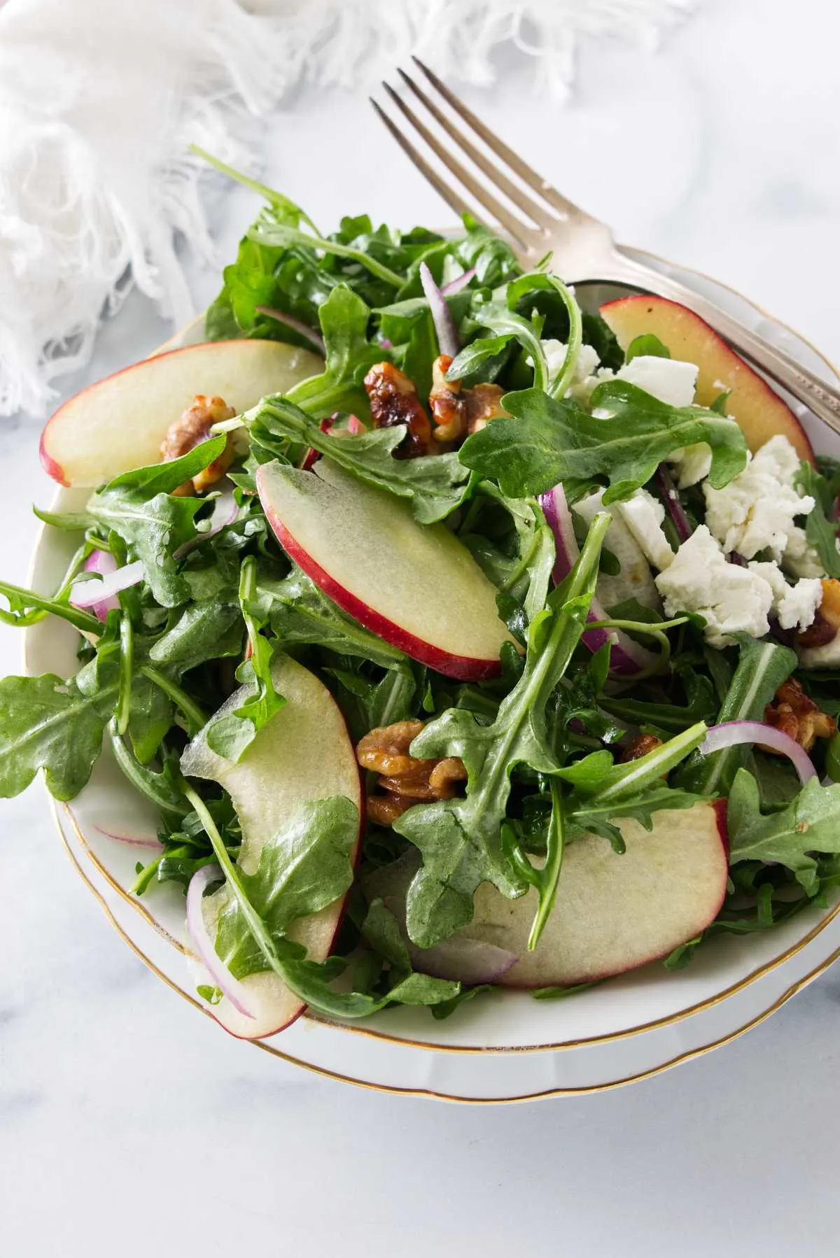 Overhead view of a serving of arugula apple salad and a dinner fork.