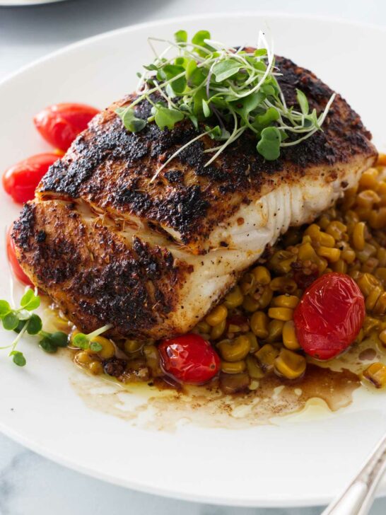 a serving of blackened halibut on a bed of chipotle corn salsa and sauteed tomatoes.