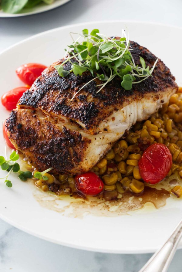 a serving of blackened halibut on a bed of chipotle corn salsa and sauteed tomatoes.