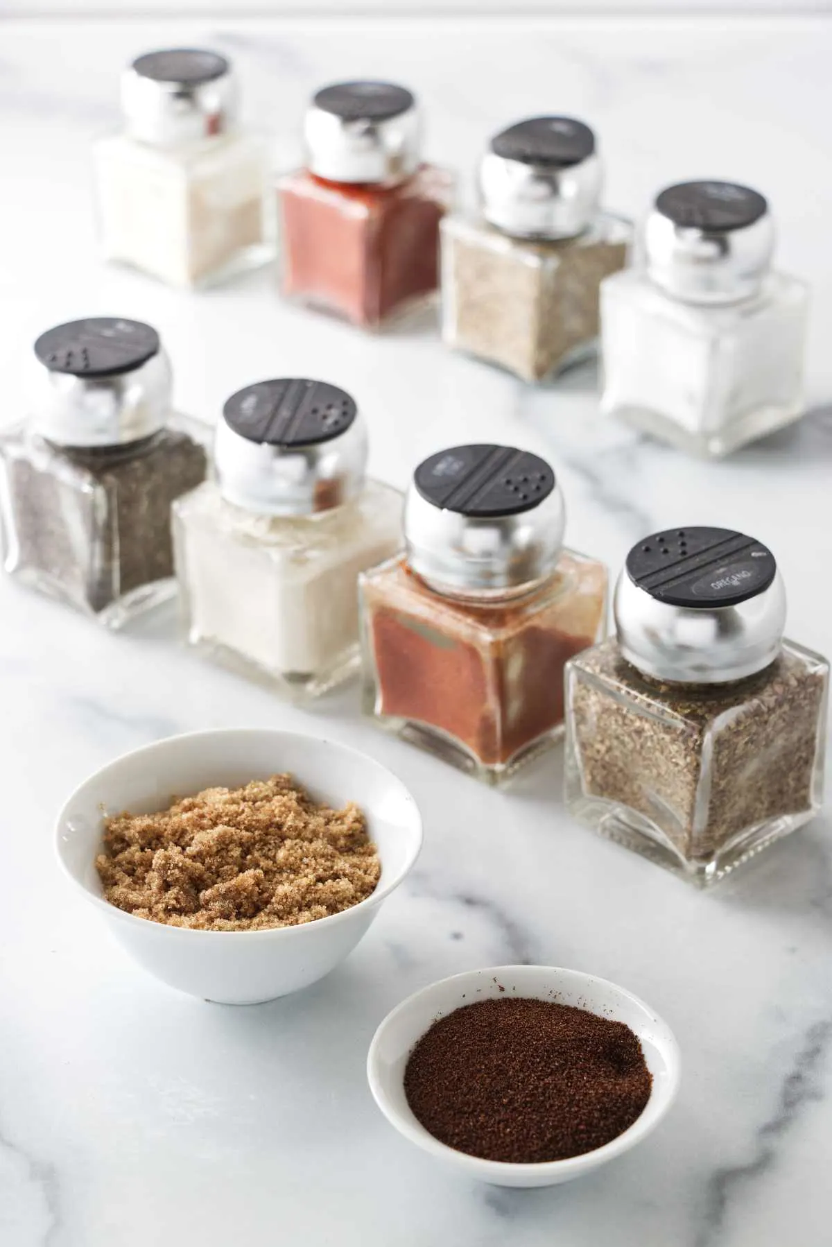 Spices to make the blackened seasoning mix: Back row: garlic, paprika, thyme, salt. Middle row: Black pepper, onion powder, cayenne, oregano. Front row: Brown sugar and espresso coffee powder.